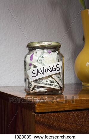 Stock Photo - A jar full of US paper currency labeled SAVINGS. Fotosearch