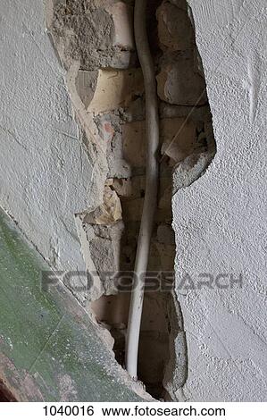 A large crack in a wall exposing a cable View Large Photo Image Stock Photograph - A large crack in a wall exposing a cable. Fotosearch