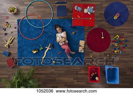 A little girl lying on a rug hugging stuffed animals, overhead view View Large Photo Image Stock Photograph - A little girl lying on a rug hugging stuffed animals, overhead view. Fotosearch