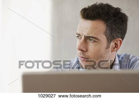 A man day dreaming in his home office View Large Photo Image Stock Photo - A man day dreaming in his home office. Fotosearch