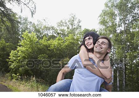 A man giving his girlfriend a piggyback ride through a field View Large Photo Image Stock Photo - A man giving his girlfriend a piggyback ride through a field. Fotosearch