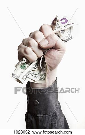 Stock Image - A man gripping a wad of US paper currency, close-up of hand. Fotosearch