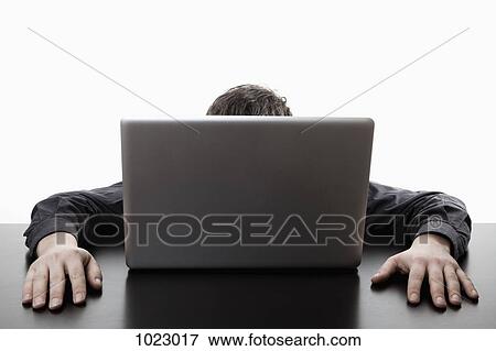 Stock Photo - A man hiding behind a laptop. Fotosearch