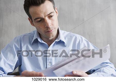 Stock Photograph - A man looking through his mail. Fotosearch