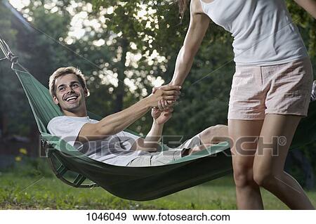 A man lying in a hammock pulling his girlfriend down View Large Photo Image Stock Photo - A man lying in a hammock pulling his girlfriend down. Fotosearch
