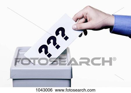 Stock Photograph - A man putting a ballot with question marks on it into a ballot box, close-up hands. Fotosearch