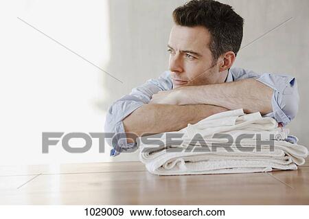 A man resting on a stack of folded laundry, day dreaming View Large Photo Image Stock Photo - A man resting on a stack of folded laundry, day dreaming. Fotosearch