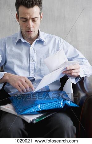 Stock Image - A man sifting through a pile of mail. Fotosearch