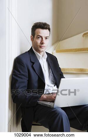 A man sitting on a staircase using a laptop View Large Photo Image Picture - A man sitting on a staircase using a laptop. Fotosearch
