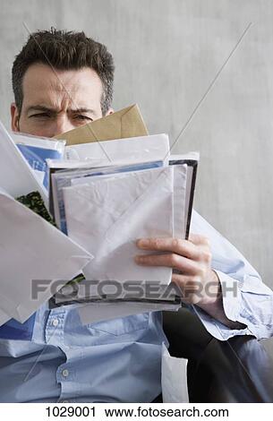 A man squinting at a bunch of mail he's holding View Large Photo Image Stock Image - A man squinting at a bunch of mail he's holding. Fotosearch