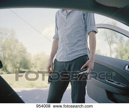 A man standing outside a car, midsection View Large Photo Image Stock Photo - A man standing outside a car, midsection. Fotosearch