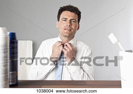 A man tying a tie in a bathroom View Large Photo Image Picture - A man tying a tie in a bathroom . Fotosearch