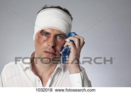 A man with bruises and a bandaged head holding an ice pack to his face View Large Photo Image Stock Photo - A man with bruises and a bandaged head holding an ice pack to his face. Fotosearch