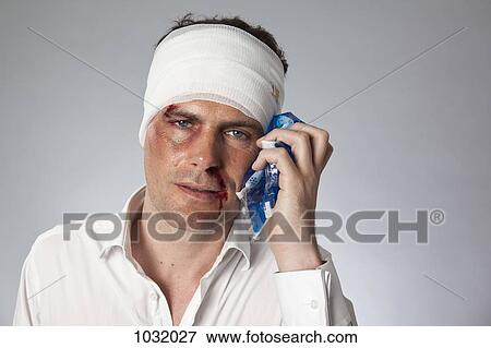 A man with bruises and a bandaged head holding an ice pack to his face View Large Photo Image Stock Photo - A man with bruises and a bandaged head holding an ice pack to his face. Fotosearch