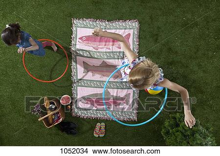 Picture - A mother and daughter using hula hoops at a picnic in the park, overhead view. Fotosearch