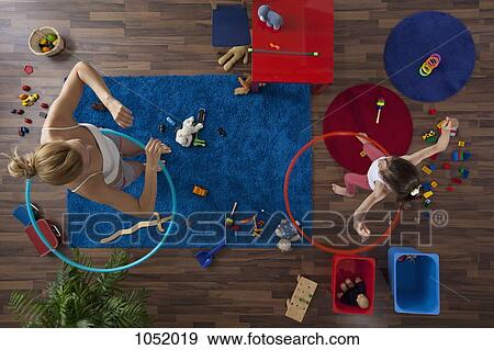 A mother and daughter using hula hoops in their living room, overhead view View Large Photo Image Stock Photo - A mother and daughter using hula hoops in their living room, overhead view. Fotosearch