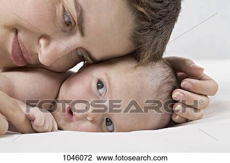 A mother cuddling a baby lying on its stomach View Large Photo Image Stock Image - A mother cuddling a baby lying on its stomach. Fotosearch