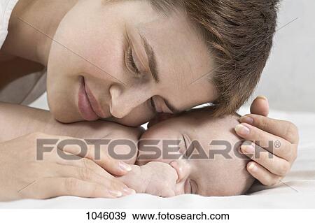 Stock Photo - A mother cuddling her sleeping baby. Fotosearch