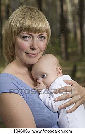 A mother holding her baby, outdoors View Large Photo Image Stock Photography - A mother holding her baby, outdoors. Fotosearch