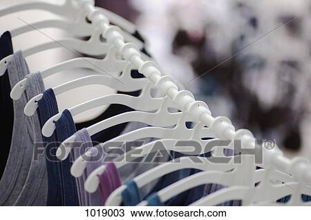 A row of t-shirts hanging on hangers in a retail shop View Large Photo Image Stock Image - A row of t-shirts hanging on hangers in a retail shop. Fotosearch