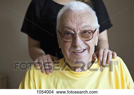 A senior man in a nursing home, hands on his shoulders, focus on him View Large Photo Image Picture - A senior man in a nursing home, hands on his shoulders, focus on him. Fotosearch