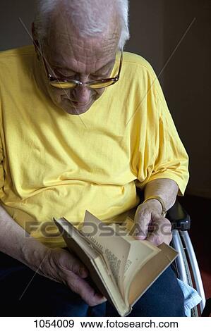 A senior man in a wheelchair flipping through a book View Large Photo Image Stock Photo - A senior man in a wheelchair flipping through a book. Fotosearch