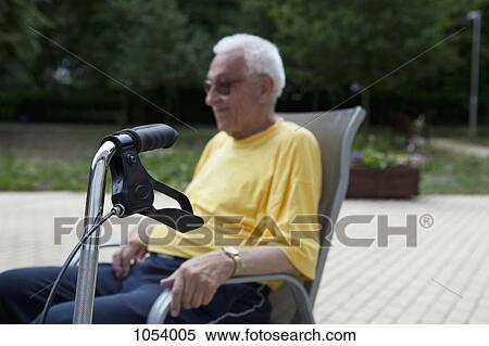 A senior man sitting in a chair, the handle of his walker in the foreground, focus on foreground View Large Photo Image Stock Photography - A senior man sitting in a chair, the handle of his walker in the foreground, focus on foreground. Fotosearch