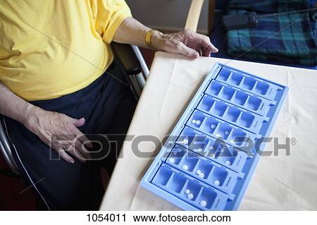 A senior man sitting next to a weekly pill organizer, focus on object View Large Photo Image Stock Image - A senior man sitting next to a weekly pill organizer, focus on object. Fotosearch