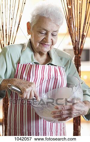 A senior woman mixing ingredients in a bowl View Large Photo Image Stock Photo - A senior woman mixing ingredients in a bowl. Fotosearch