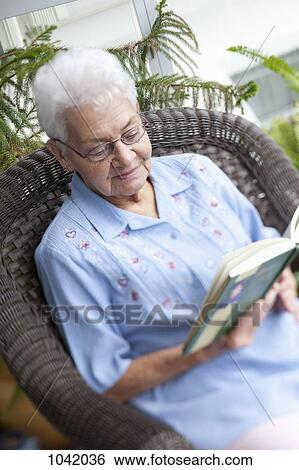 A senior woman reading in an armchair View Large Photo Image Stock Photograph - A senior woman reading in an armchair. Fotosearch