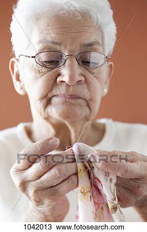 A senior woman stitching fabric View Large Photo Image Stock Image - A senior woman stitching fabric. Fotosearch