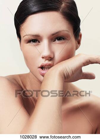 Stock Photo - A shirtless woman wiping her mouth with the back of her hand. Fotosearch