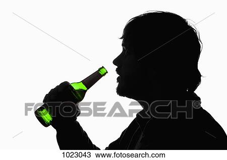 Stock Image - A silhouetted man about to drink from a beer bottle. Fotosearch