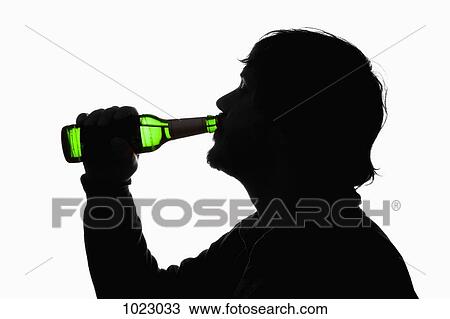 Stock Image - A silhouetted man drinking beer from a bottle. Fotosearch