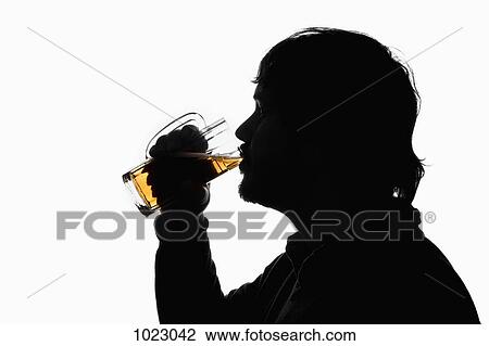 Stock Image - A silhouetted man drinking beer from a glass. Fotosearch