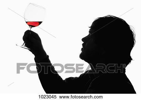 A silhouetted man holding up a glass of red wine to examine it View Large Photo Image Stock Photography - A silhouetted man holding up a glass of red wine to examine it. Fotosearch