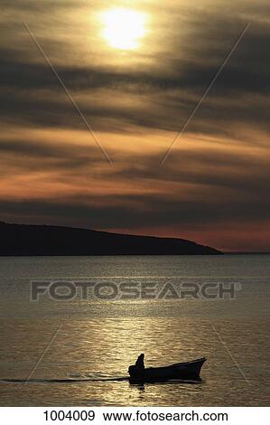 A silhouetted person in a motorboat near Cres on the Adriatic Sea, Croatia View Large Photo Image Stock Photo - A silhouetted person in a motorboat near Cres on the Adriatic Sea, Croatia. Fotosearch