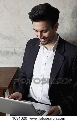 A smiling businessman working on a laptop, high angle view View Large Photo Image Stock Image - A smiling businessman working on a laptop, high angle view. Fotosearch