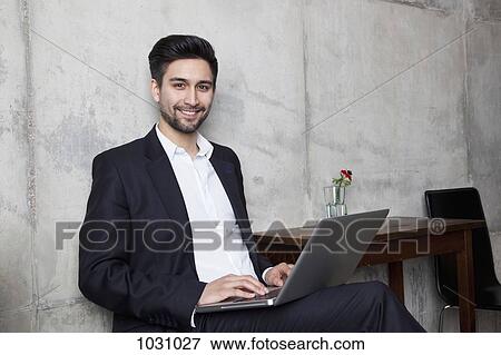 A smiling businessman working on a laptop View Large Photo Image Stock Photo - A smiling businessman working on a laptop. Fotosearch