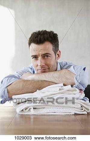 A smiling man resting on a stack of folded laundry View Large Photo Image Stock Image - A smiling man resting on a stack of folded laundry. Fotosearch