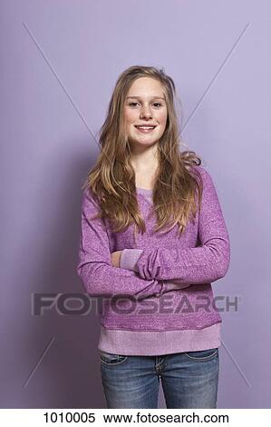 Stock Photography - A smiling teenage girl with arms crossed, portrait, studio shot. Fotosearch