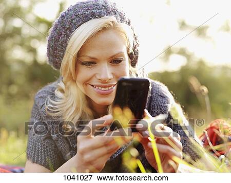 A smiling woman looking at her smart phone View Large Photo Image Stock Photo - A smiling woman looking at her smart phone. Fotosearch