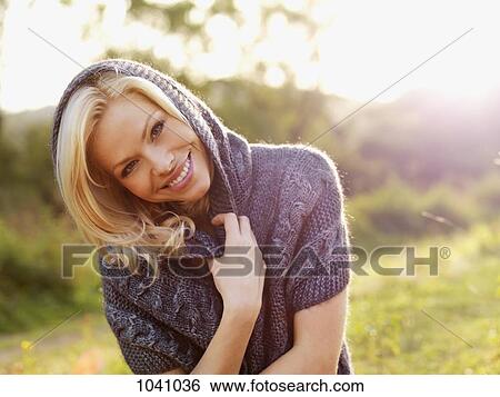Stock Photograph - A smiling woman relaxing in the sun on an autumn day. Fotosearch