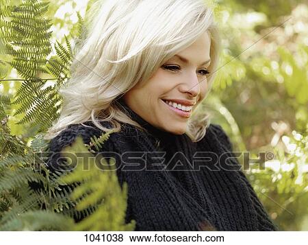 A smiling woman surrounded by lush foliage View Large Photo Image Stock Photo - A smiling woman surrounded by lush foliage. Fotosearch