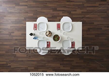 Stock Photography - A table with place settings, wine, water, salad and bread, no people, overhead view. Fotosearch
