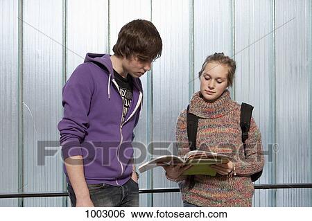 A teenage boy and girl looking at a school workbook together View Large Photo Image Stock Photograph - A teenage boy and girl looking at a school workbook together. Fotosearch