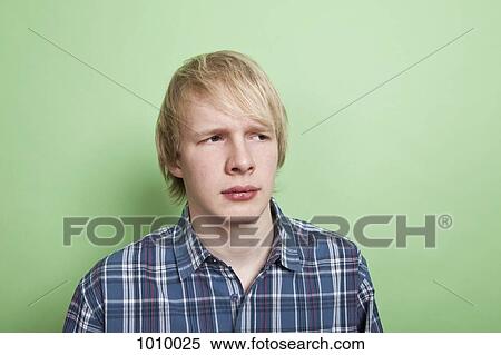 Stock Photography - A teenage boy looking off to the side with suspicion, portrait, studio shot. Fotosearch