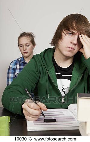 A teenage boy looking worried in a classroom, girl in background View Large Photo Image Stock Image - A teenage boy looking worried in a classroom, girl in background. Fotosearch