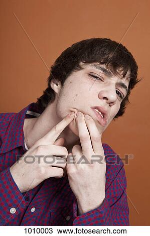 A teenage boy popping a zit on his face, portrait, studio shot View Large Photo Image Stock Image - A teenage boy popping a zit on his face, portrait, studio shot. Fotosearch