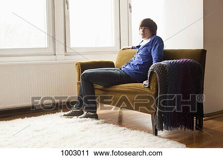 Stock Image - A teenage boy sitting on a couch. Fotosearch